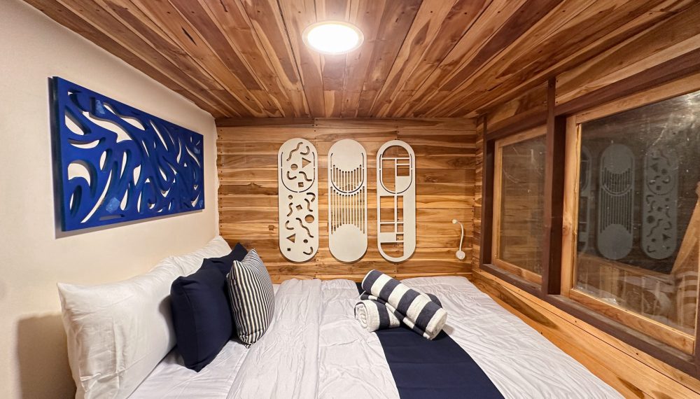 Azure room on Vhalé Liveaboard with natural wood finish and elegant décor and sharing bathroom