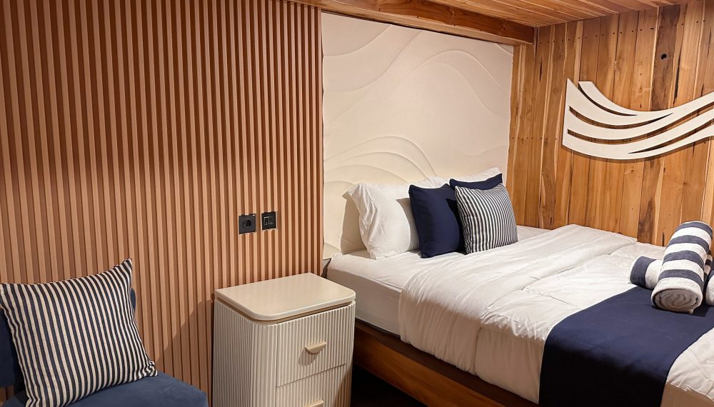 Oceanic private room on Vhalé phinisi featuring kingbed, sofa and modern wooden design