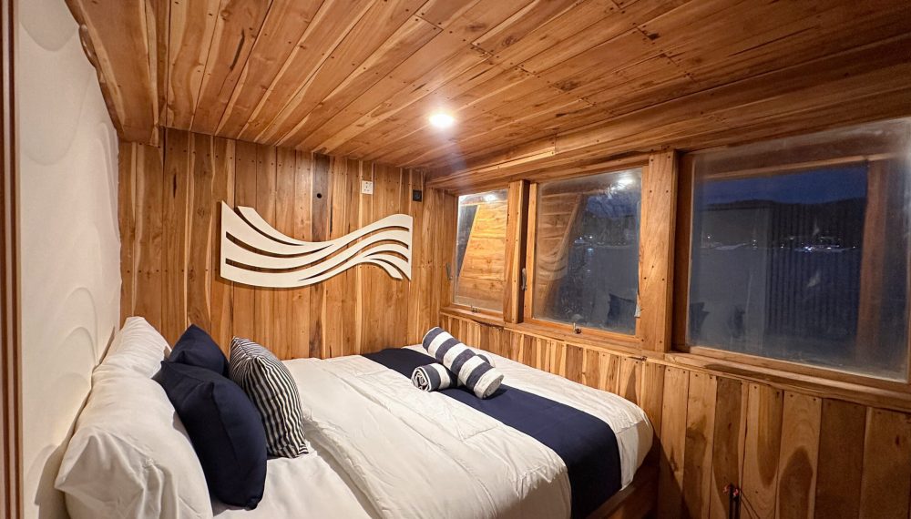 Oceanic private room on Vhalé phinisi featuring kingbed, sofa and modern wooden design